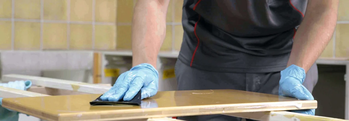 Person schleift eine Holzoberfläche mit Schleifpapier.